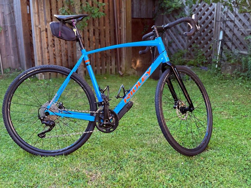 Gravelbike in hellblau mit orangen Akzenten – einsatzbereit für Stadt, Schotter und Bergtouren
