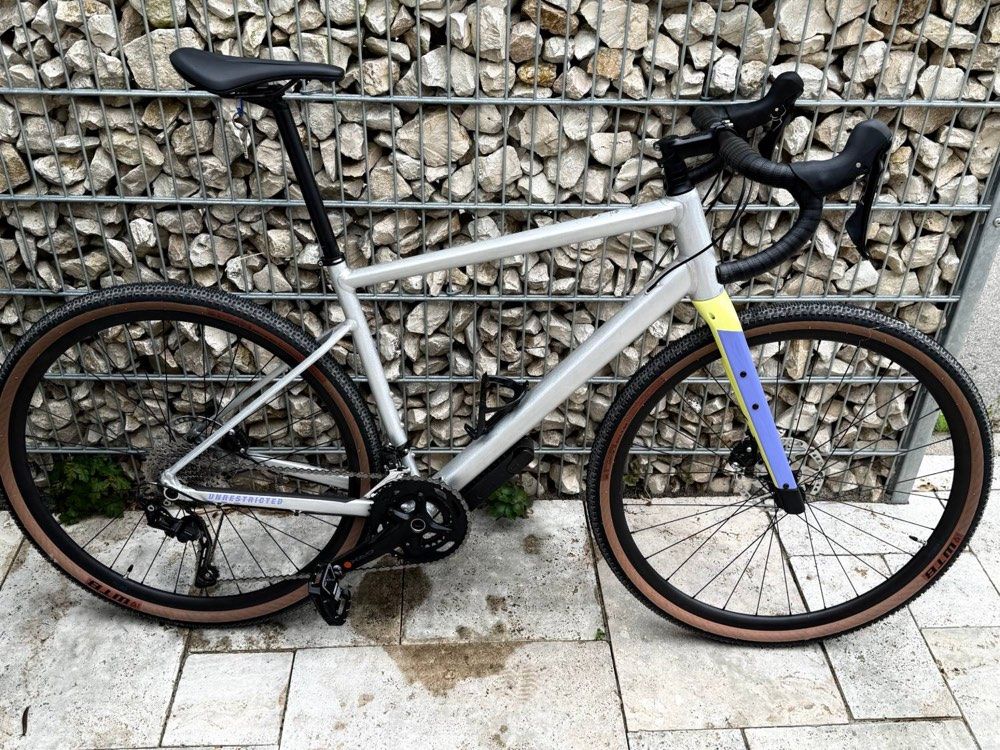 Gravelbike in silber mit farbig abgesetzter Gabel – einsatzbereit für Stadt, Schotter und Bergtouren